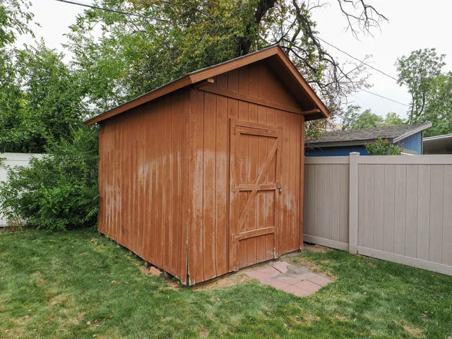 Wood-sided storage shed with a gabled roof and a wooden door