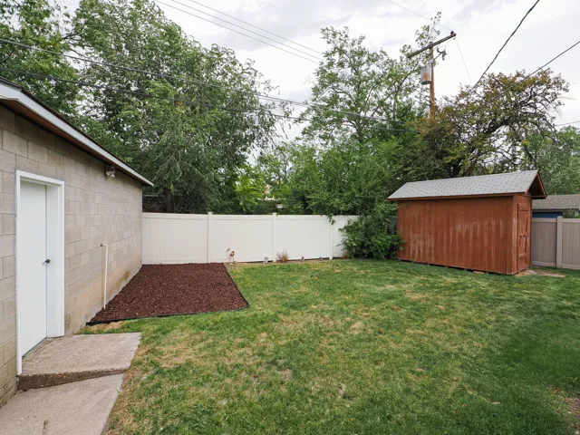 Expansive yard featuring a manicured lawn, a privacy fence, and a storage shed