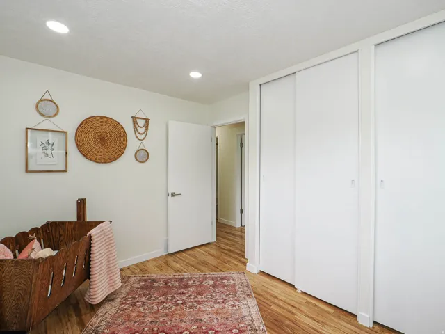 Recessed ceiling lighting, wood-finish flooring, white walls, and multiple sliding closet doors