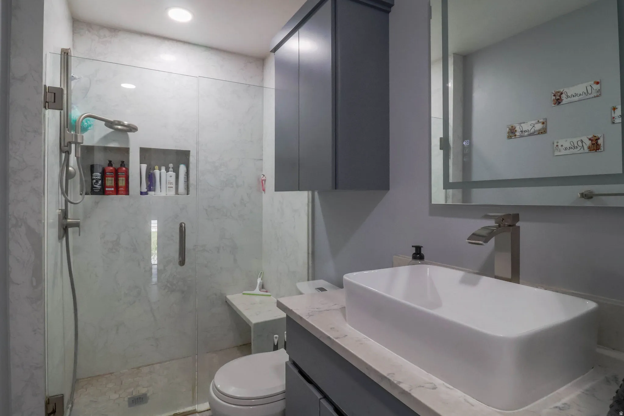 Glass-enclosed shower with dual recessed niches and a built-in bench