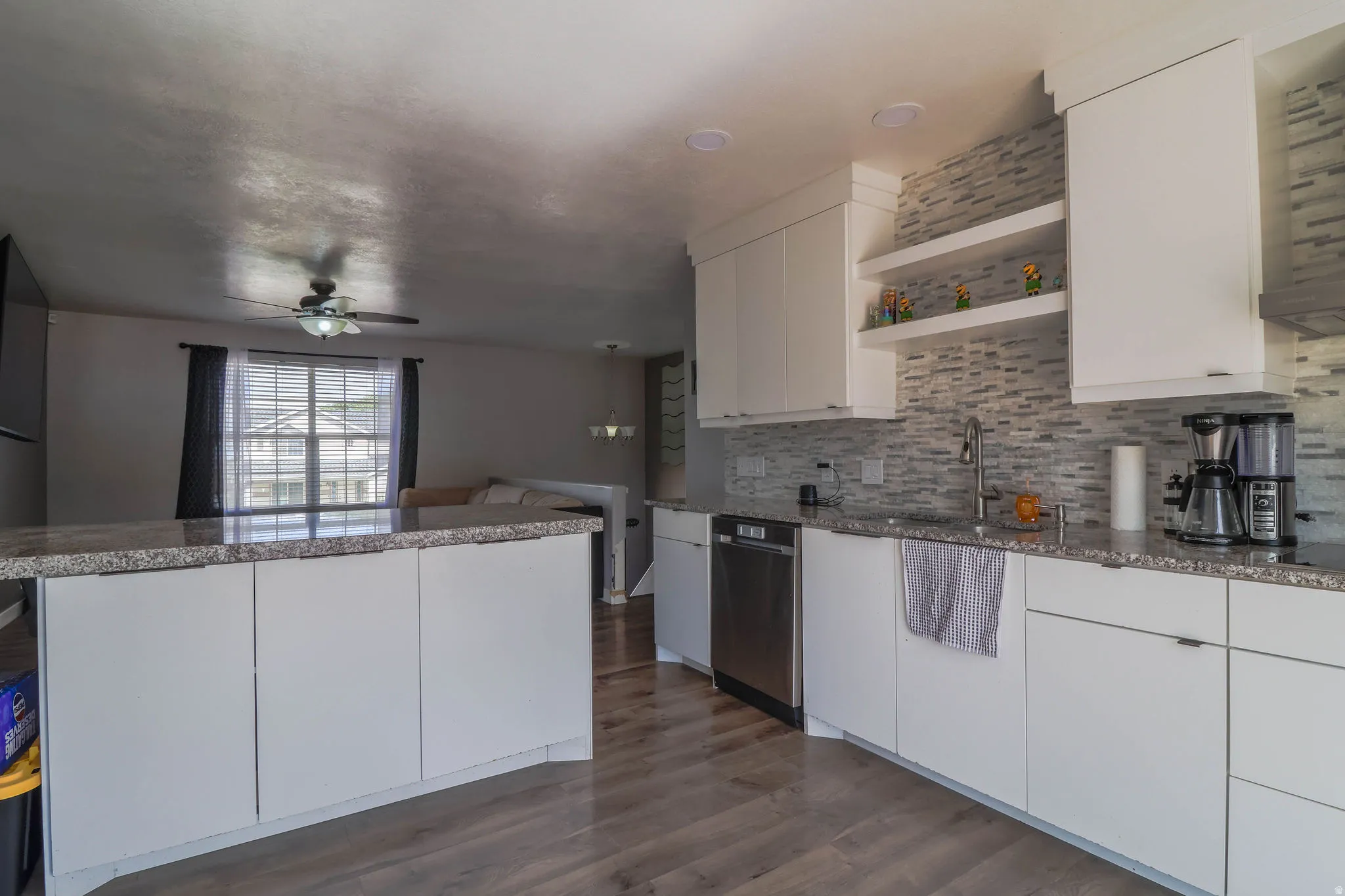 Kitchen featuring white cabinetry, stone countertops, stainless steel appliances, and a tiled backsplash