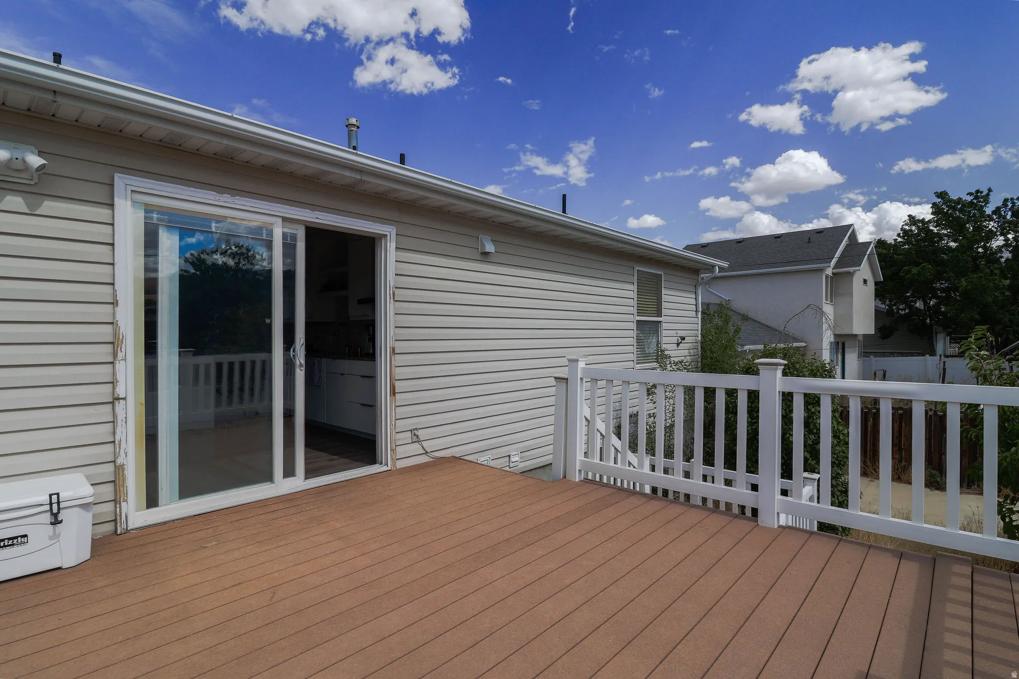 Composite decking with white railing, siding exterior, and sliding glass door