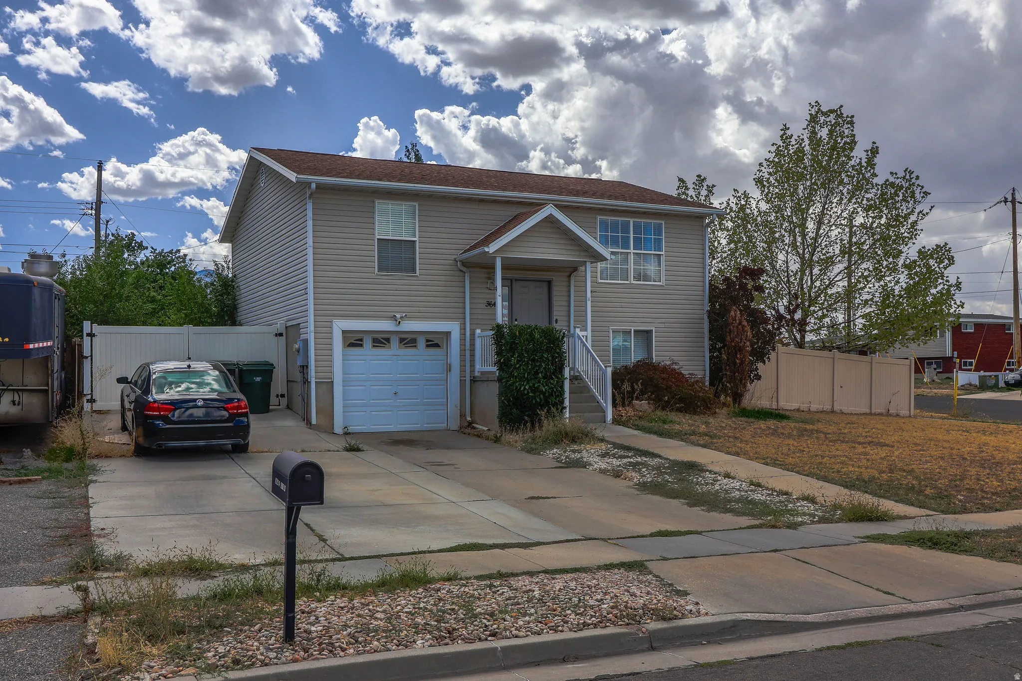 Two-story residence with light-toned siding, attached single-car garage, front porch with white railings, and a concrete driveway
