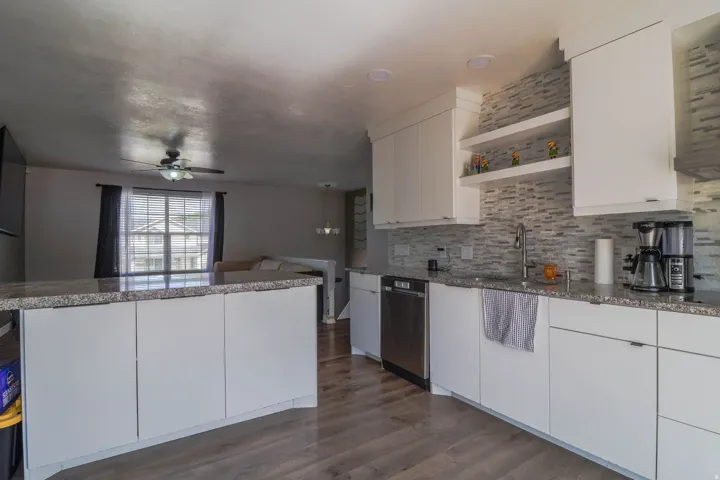 Kitchen featuring white cabinetry, stone countertops, stainless steel appliances, and a tiled backsplash