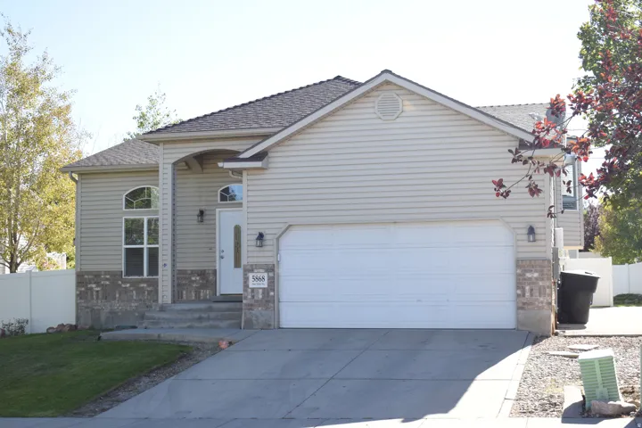Two-car garage, stone façade accents, arched entry with transom window, and a gabled roofline