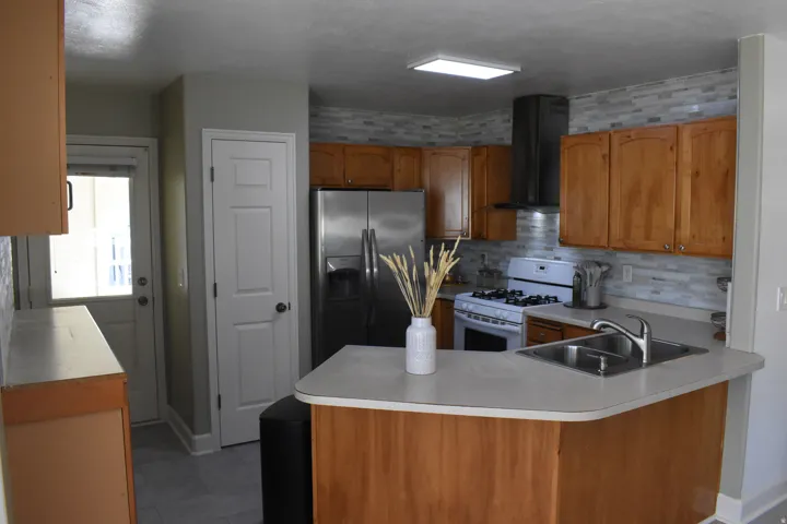 Kitchen featuring wood cabinetry, stainless steel appliances, a tile backsplash, and a breakfast bar with an undermount sink