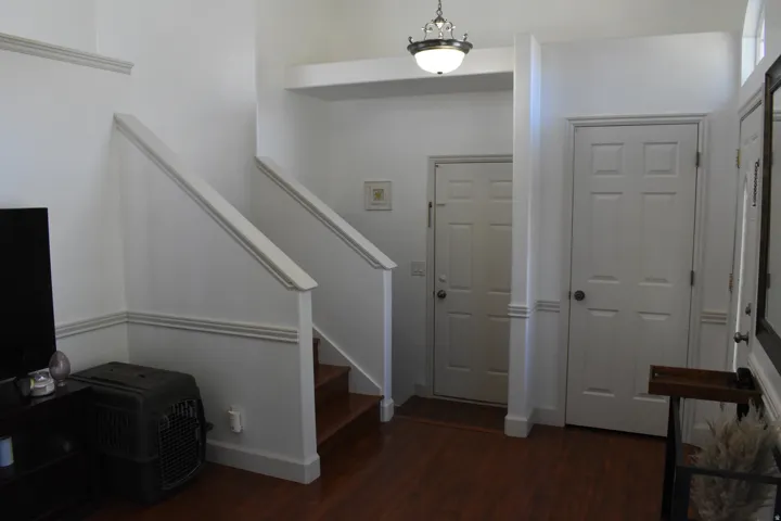 Entry foyer featuring wood-finish flooring, a staircase with painted handrails, and paneled doors