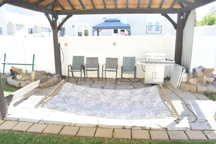 Outdoor living area with a covered patio, flagstone pavers, privacy fencing, and a built-in fire pit