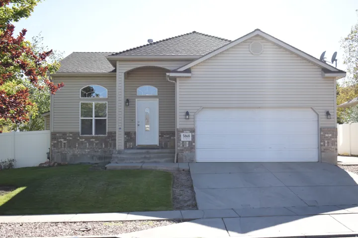 Tan siding exterior with brick accents, an attached two-car garage, and a concrete driveway