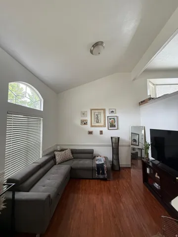 Vaulted ceilings, a half-moon accent window, and wood-finish flooring define this living space