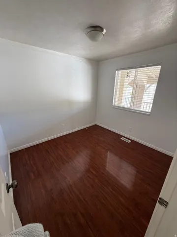 Wood-finish flooring, white walls, and a flush mount ceiling light