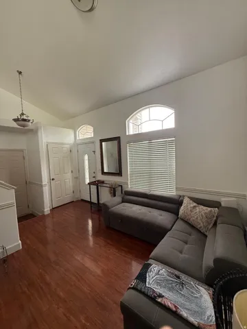 Vaulted ceiling, wood-finish flooring, arched transom windows, entry door with decorative glass, wainscoting