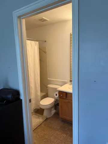 Bathroom featuring a shower/tub combination, pedestal toilet, and a vanity with a white countertop and wood-finish cabinetry