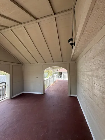 Covered porch with a pitched ceiling, exterior wall sconce, and a wood-finish floor