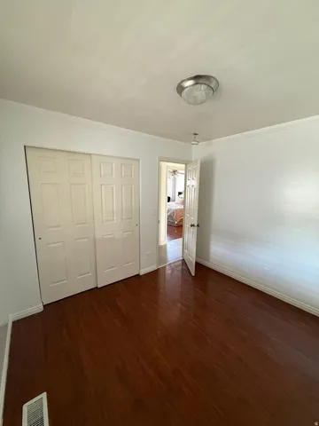 Warm wood-finish flooring, white walls, and a ceiling-mounted light fixture