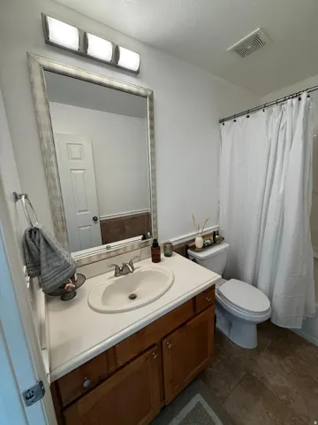 Vanity with an integrated sink, wood-finish cabinetry, and a large wall mirror