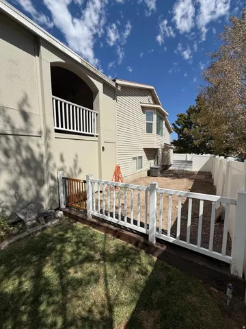 Exterior balcony with white railing, beige stucco siding, beige horizontal siding, bay window, and white privacy fencing