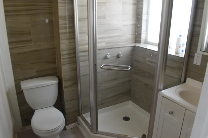 Glass-enclosed shower with a corner bench, tile surround, and a single-handle faucet