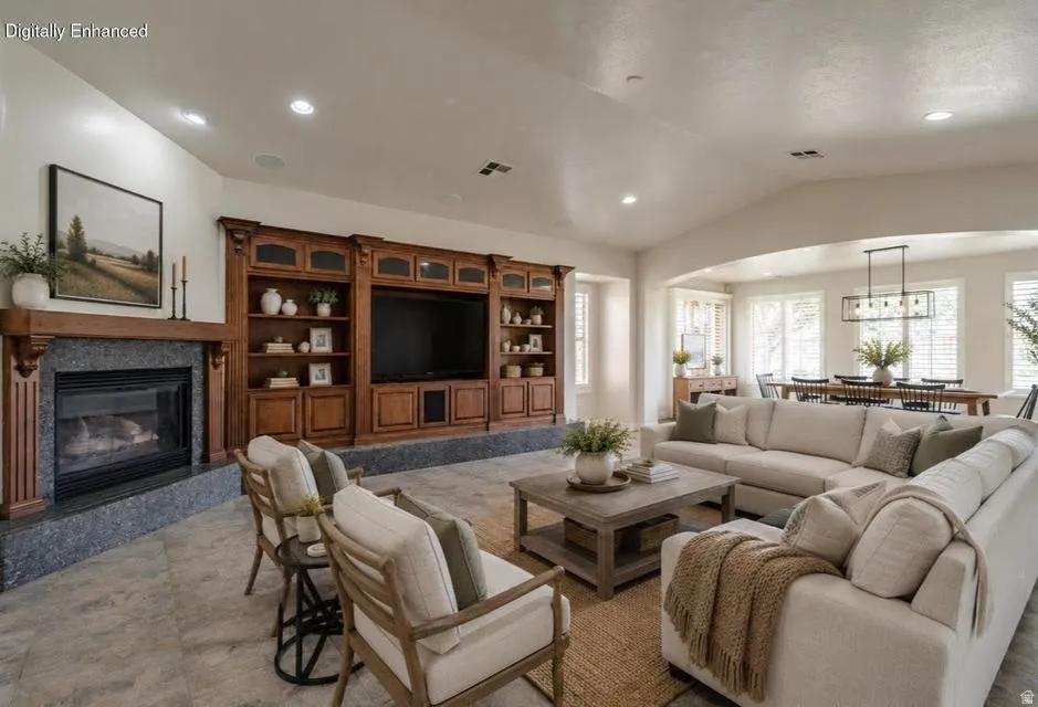 Spacious living area featuring a fireplace with a wood mantle, built-in entertainment center, vaulted ceiling, and recessed lighting