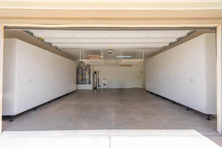 Attached garage featuring extensive perimeter storage cabinetry, built-in overhead storage racks, a utility sink, and concrete flooring