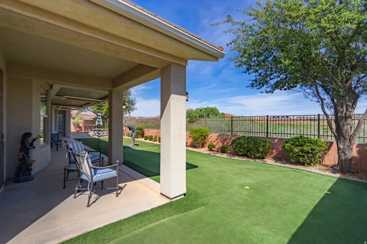 Covered patio with concrete flooring, putting green, and mature tree