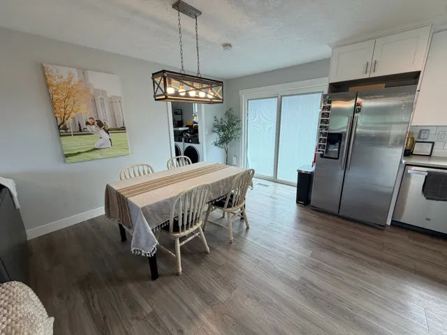 Wood-finish flooring, white cabinetry, stainless steel appliances, and a sliding glass door