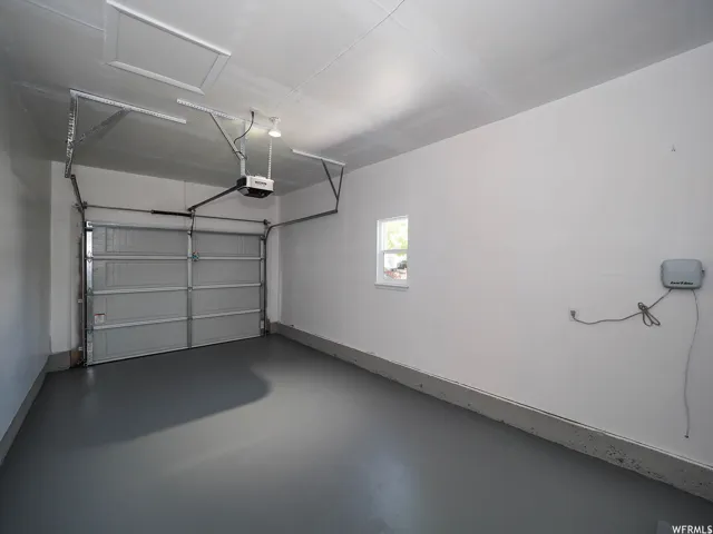 Garage featuring an automatic overhead door, a single-pane window, and a finished floor
