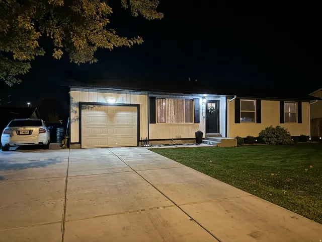 Exterior featuring a concrete driveway, attached garage, well-maintained lawn, and a dark-toned entry door
