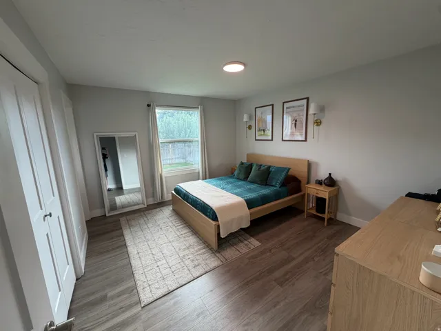 Wood-finish flooring throughout, light gray wall paint, and a window providing natural illumination