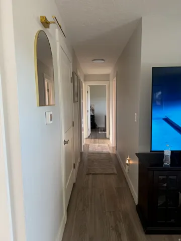 Hallway with wood-finish flooring, white walls, and flush-mount ceiling lighting