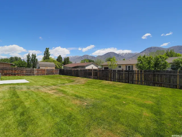 Expansive green lawn with a concrete patio pad, surrounded by a wood privacy fence
