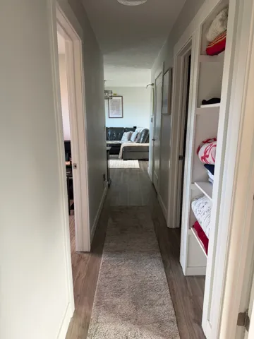 Hallway featuring wood-finish flooring, recessed lighting, and built-in shelving