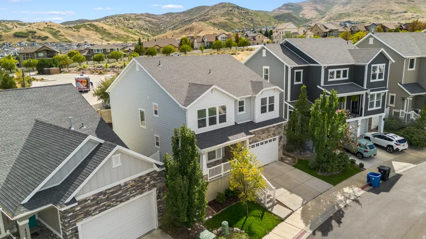 Attractive home showcasing beautiful light blue siding with refined stone accents. An integrated two-car garage and inviting front porch with white railings create both functionality and a warm, welcoming first impression.