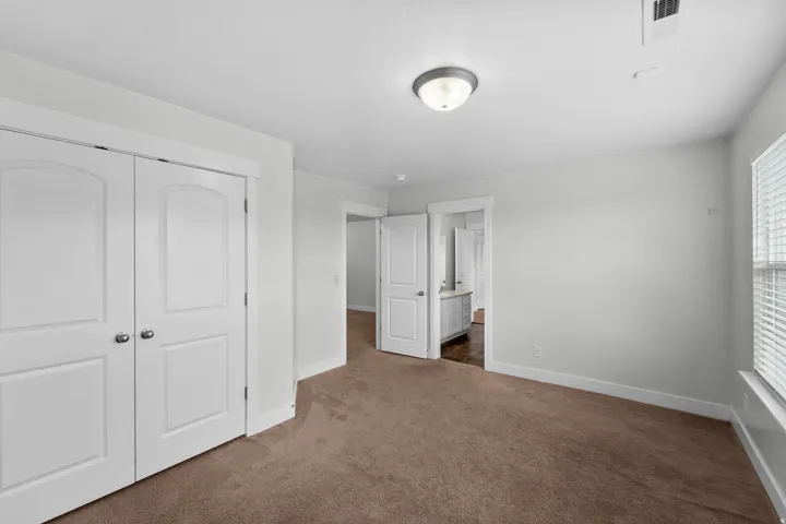 Bright and airy secondary bedroom featuring an impressive triple window array that floods the space with natural light and offers beautiful views. Serene neutral wall color creates a calm, versatile backdrop perfect for any décor style. Recessed lighting