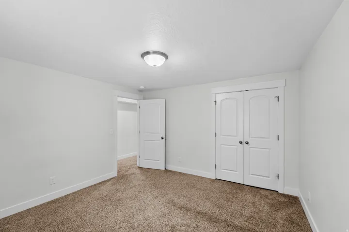 Versatile basement bedroom or guest room featuring bright, airy aesthetics perfect for welcoming guests or creating a secondary sleeping space. Recessed lighting illuminates the room with a soft, even glow, while crisp white walls create a fresh, serene e