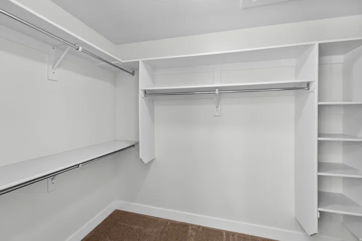 Spacious master walk-in closet offering excellent organization and storage capabilities. Multiple hanging rods provide ample space for clothing and accessories, while thoughtfully designed built-in shelving maximizes vertical storage for folded items, sho