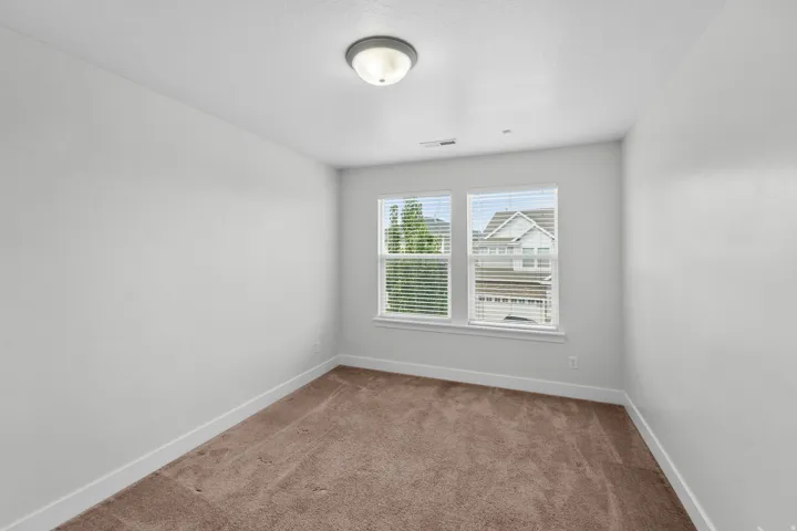Comfortable secondary bedroom showcasing soothing neutral wall finishes that provide a blank canvas for personalization. Luxurious plush carpeting adds softness and warmth, creating an inviting atmosphere perfect for relaxation. Refined white trim work ad