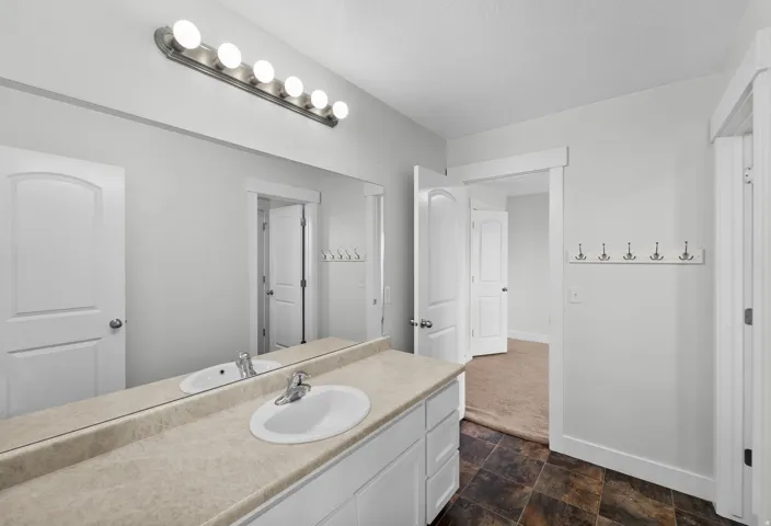 Well-designed secondary bathroom featuring a functional dual vanity with integrated sinks, perfect for busy households and guest accommodations. Polished brushed nickel fixtures add contemporary style and durability, while a generous large mirror enhances