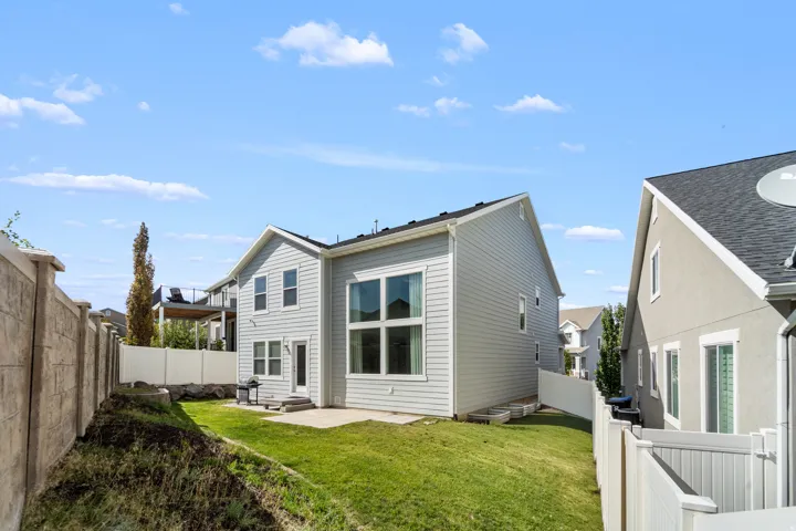 Charming two-story home featuring light-colored siding and thoughtfully designed outdoor spaces. Enjoy a private patio perfect for entertaining and relaxing, complemented by a beautifully sloped grassy yard ideal for families and outdoor activities.