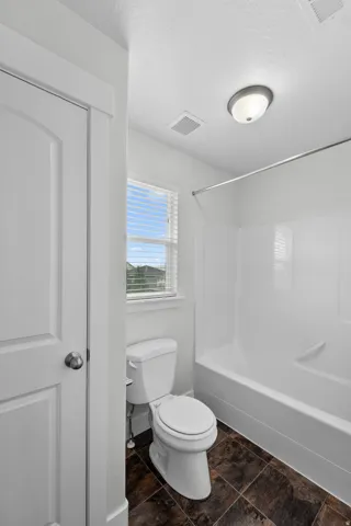Charming second-floor bathroom featuring a crisp white shower and tub combination that provides versatile bathing options. A window with blinds allows natural light to brighten the space while offering privacy control, creating an airy, welcoming atmosphe