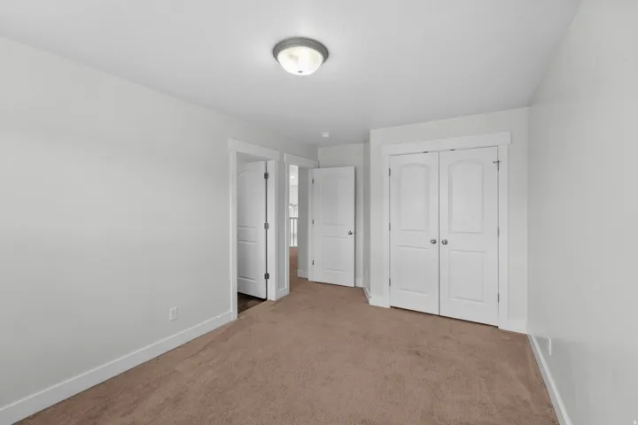 Comfortable secondary bedroom showcasing soothing neutral wall finishes that provide a blank canvas for personalization. Luxurious plush carpeting adds softness and warmth, creating an inviting atmosphere perfect for relaxation. Refined white trim work ad