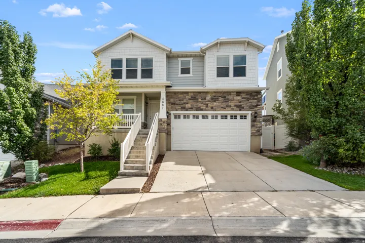 Attractive two-story exterior with distinctive stone accents and light siding. Offering an integrated two-car garage and an inviting front porch adorned with white railings—the perfect welcome home.