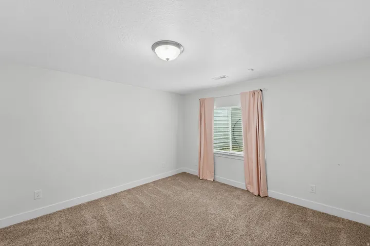 Versatile basement bedroom or guest room featuring bright, airy aesthetics perfect for welcoming guests or creating a secondary sleeping space. Recessed lighting illuminates the room with a soft, even glow, while crisp white walls create a fresh, serene e