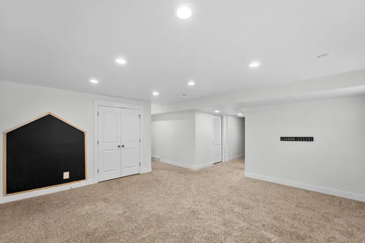 Fun and functional basement bedroom perfect for kids, featuring a creative chalkboard wall ideal for drawing, learning, and imaginative play. Bright recessed lighting illuminates the space, while neutral wall paint provides a clean, versatile backdrop tha