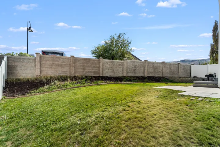 Expansive backyard oasis offering excellent privacy with a concrete fence and complementary white vinyl fencing. The thoughtfully designed patio area features quality concrete pavers, creating an ideal outdoor entertaining space for family gatherings and