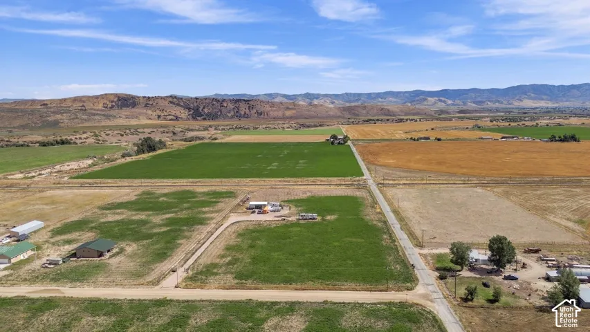 Expansive rural landscape featuring agricultural fields, multiple outbuildings, and distant mountain ranges