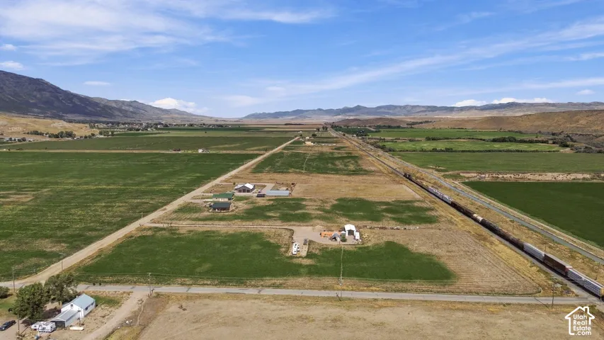 Expansive rural landscape featuring a single-story residence, a large outbuilding, and distant mountains