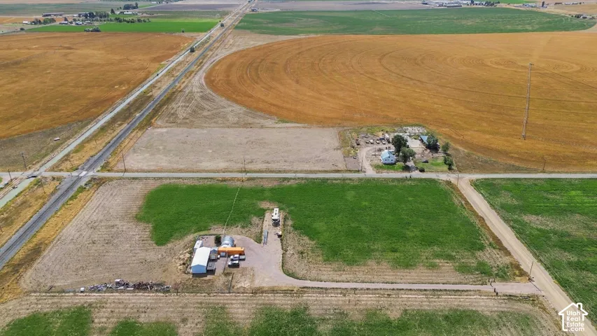 Expansive agricultural property featuring cultivated fields, a detached structure, and a residential building