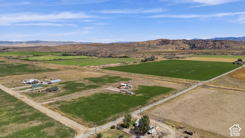 Expansive land parcels with cultivated fields, scattered residences, and distant mountain ranges