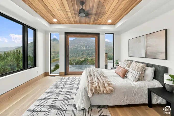 Master Bedroom with Brazilian hardwood   planking, floor-to-ceiling windows, wide-plank wood-finish flooring, and exterior door with mountain backdrop